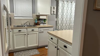 Kitchen with tasteful backsplash, white appliances, sink, white cabinets, and hardwood / wood-style floors | Image 3