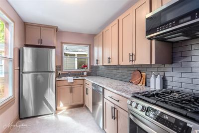 Kitchen with light stone counters, sink, stainless steel appliances, backsplash, and light brown cabinets | Image 2