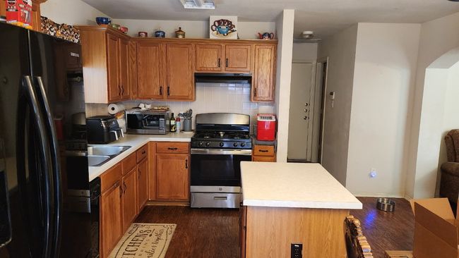 Kitchen with appliances with stainless steel finishes, under cabinet range hood, dark wood-style floors, and light countertops | Image 5