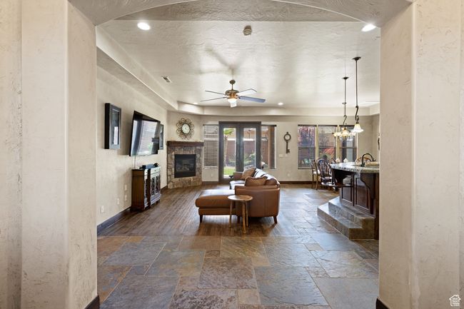 Living area with stone tile floors, a stone fireplace, ceiling fan, recessed lighting, and a chandelier | Image 47