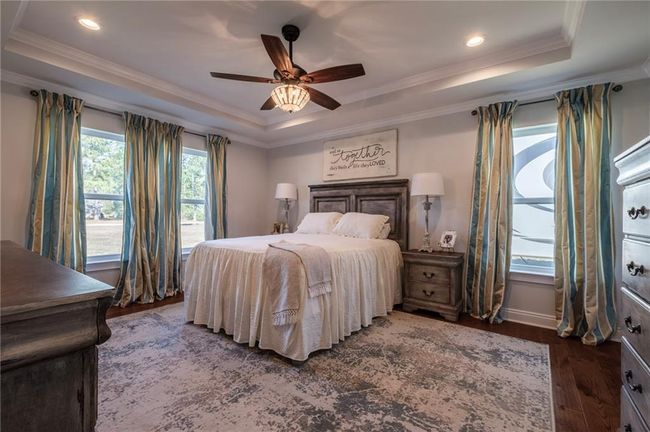 Bedroom with ornamental molding, a tray ceiling, ceiling fan, and dark wood-type flooring | Image 16