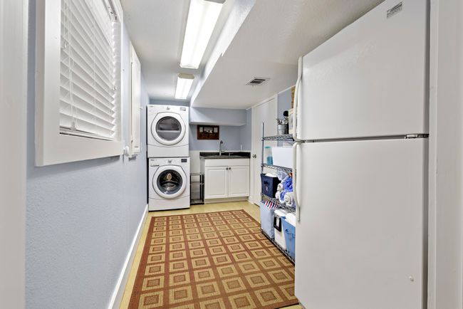 Laundry area with a sink provide space for second refridgerator and storage. | Image 19