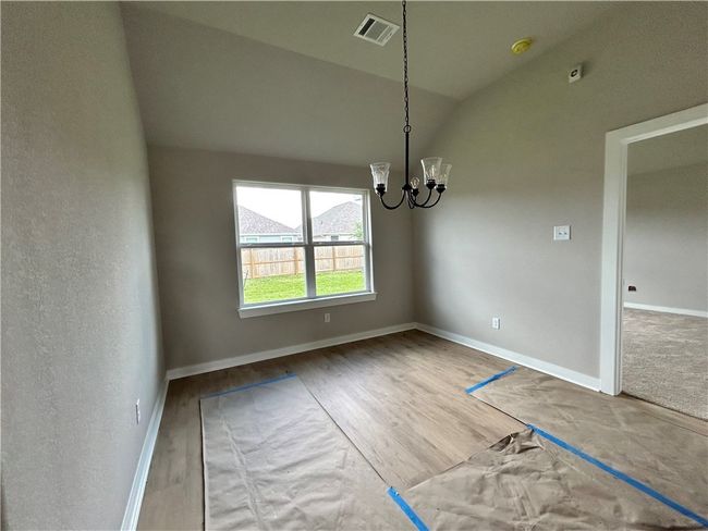 Unfurnished dining area featuring a chandelier, wood finished floors, and vaulted ceiling | Image 7
