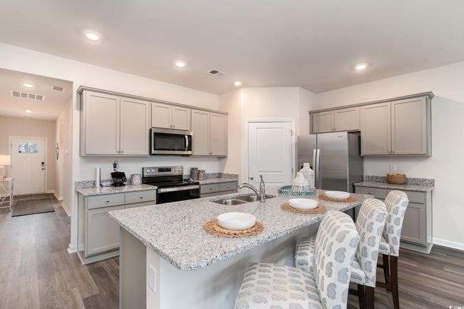 Kitchen featuring stainless steel appliances, gray cabinetry, dark wood-style floors, a kitchen breakfast bar, and recessed lighting | Image 7