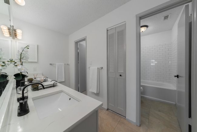 Bathroom featuring double vanity, a sink, a textured ceiling, and a closet | Image 31