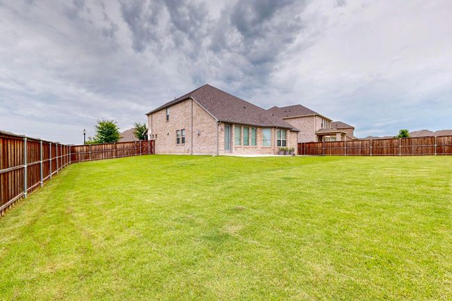 Rear view of property featuring brick siding, a fenced backyard, a patio, and a shingled roof | Image 34