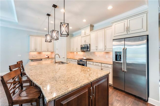 Kitchen featuring stainless steel appliances, a sink, light stone counters, crown molding, and tasteful backsplash | Image 8