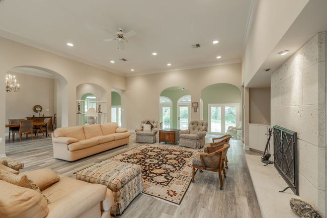 Living area with crown molding, light wood finished floors, arched walkways, a ceiling fan, and recessed lighting | Image 8