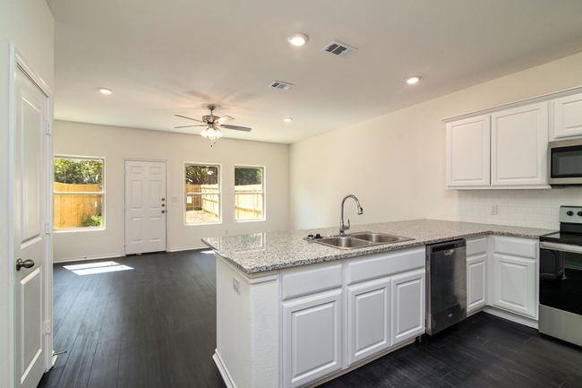 Kitchen featuring kitchen peninsula, sink, white cabinetry, and stainless steel appliances | Image 8