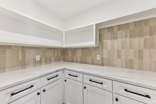An entertainer’s dream kitchen with quartz countertops and sleek white cabinetry. | Image 13