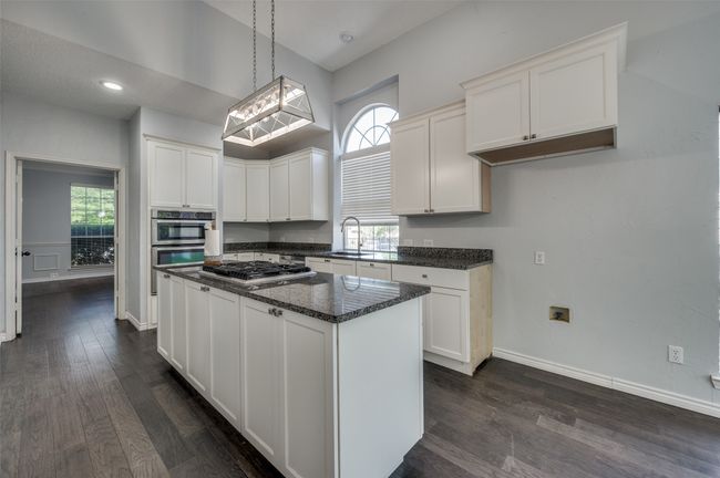 Kitchen featuring stainless steel gas stovetop, a sink, dark wood-type flooring, and white cabinetry | Image 11