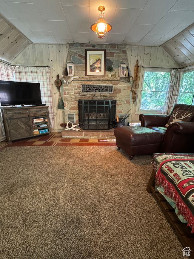 Living area with lofted ceiling, wood walls, a stone fireplace, and carpet floors | Image 5
