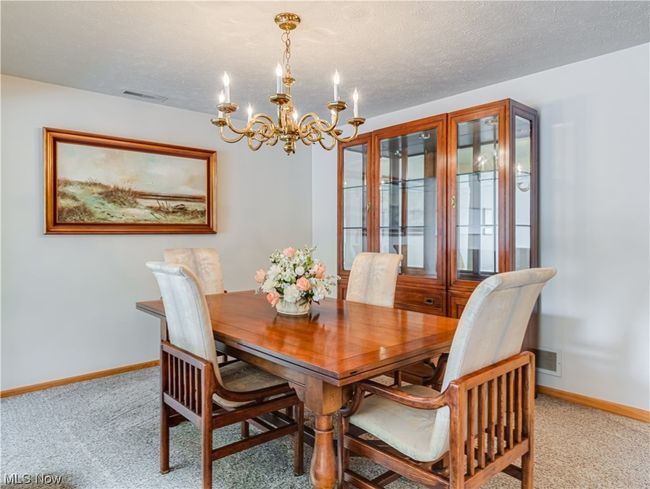 Dining area with a notable chandelier, a textured ceiling, and light carpet | Image 13
