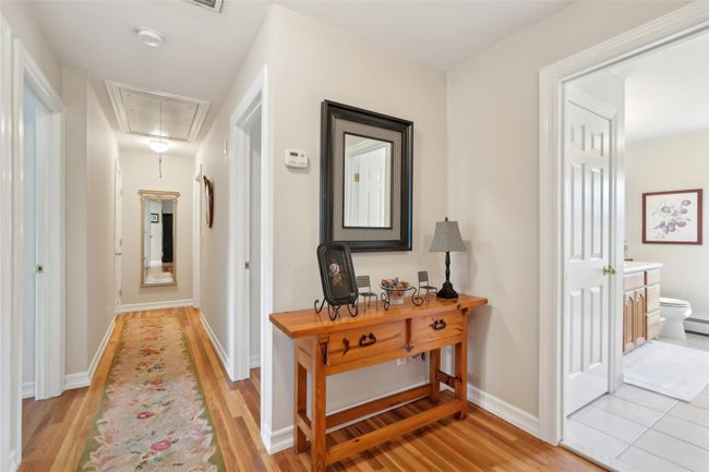 Bedroom with a baseboard heating unit, baseboard heating, wood finished floors, and visible vents | Image 28