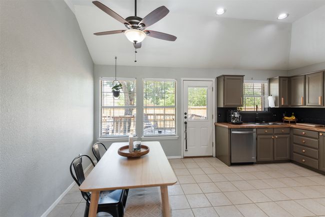 Dining area featuring dishwasher, vaulted ceiling, gray cabinets, a ceiling fan, and light tile patterned flooring | Image 10