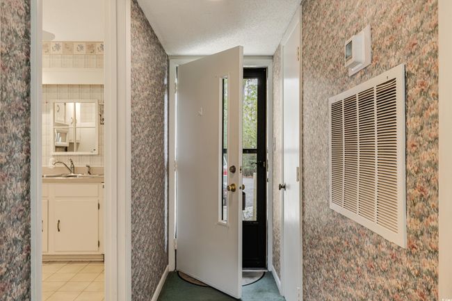 Hall featuring a sink, a textured ceiling, a heating unit, light tile patterned floors, and wallpapered walls | Image 4