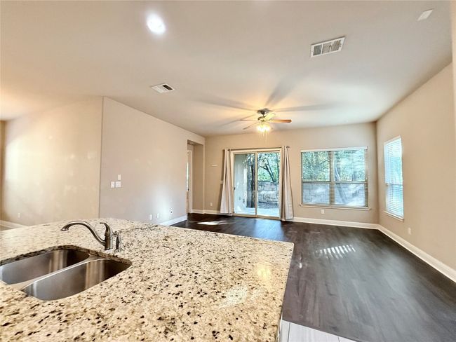 Kitchen with dark wood-type flooring, ceiling fan, light stone countertops, and open floor plan | Image 15