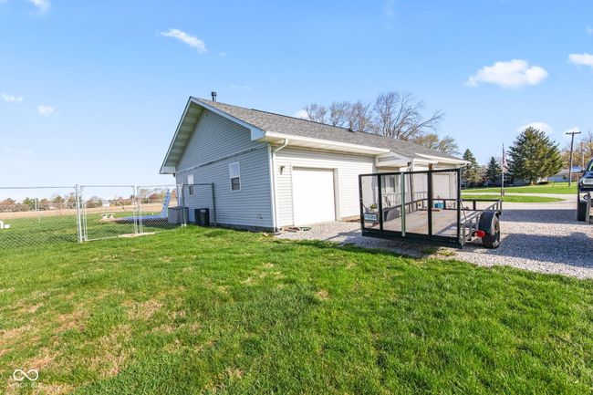 view of home's exterior with a gate, an attached garage, a wooden deck, a yard, and fence | Image 54