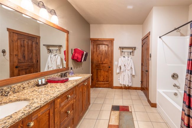 Bathroom with double vanity, shower / bath combo, tile patterned flooring, and baseboards | Image 47