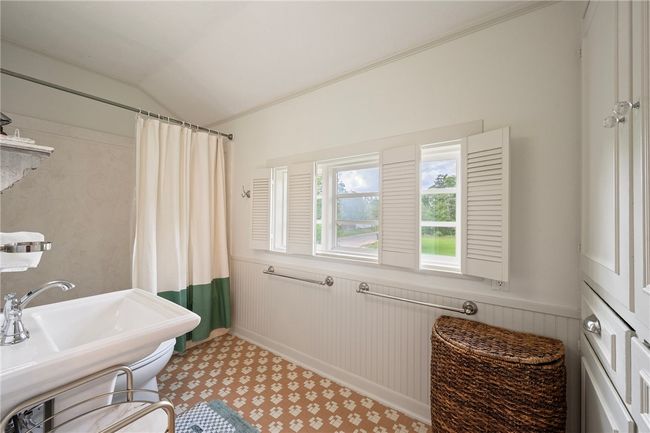 Full bathroom with wainscoting, lofted ceiling, and curtained shower | Image 30