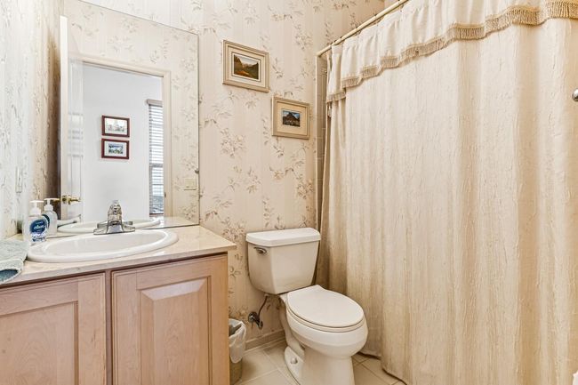 Full bathroom with wallpapered walls, toilet, tile patterned flooring, and vanity | Image 26