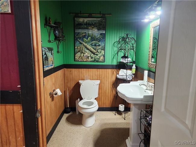 Bathroom in basement with toilet, baseboards, wood walls, and a sink | Image 16
