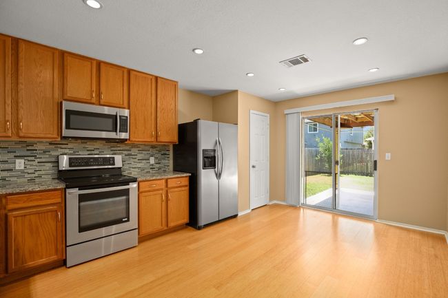 Kitchen with stainless steel appliances, light wood-style flooring, decorative backsplash, brown cabinetry, and recessed lighting | Image 7
