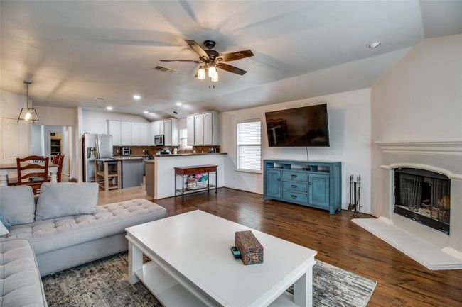 Living room with ceiling fan, lofted ceiling, dark wood-type flooring, a fireplace with raised hearth, and recessed lighting | Image 5