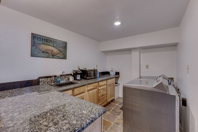 Kitchen featuring light brown cabinets, a sink, independent washer and dryer, stone finish flooring, and stainless steel microwave | Image 14
