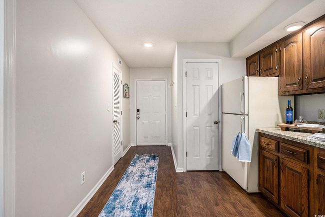 Kitchen with light countertops, freestanding refrigerator, dark wood-style flooring, recessed lighting, and dark brown cabinets | Image 6