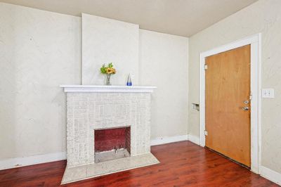 Unfurnished living room featuring a brick fireplace, hardwood / wood-style floors, and ceiling fan | Image 3