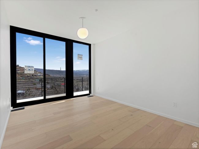 Spare room featuring visible vents, light wood finished floors, baseboards, and a wall of windows | Image 30