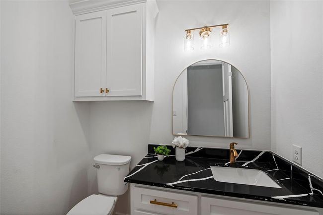 Stylish half bath featuring elegant black countertops, modern fixtures, and ample storage. | Image 29