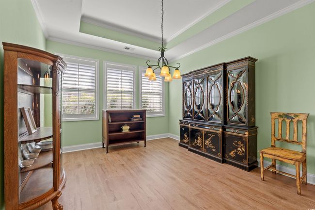 Living area with visible vents, a chandelier, crown molding, wood finished floors, and a raised ceiling | Image 15