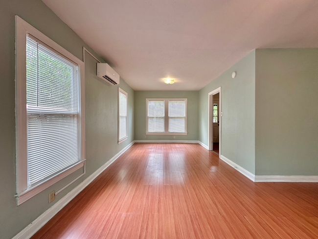 Main room featuring a wall mounted air conditioner and wood finished floors | Image 5