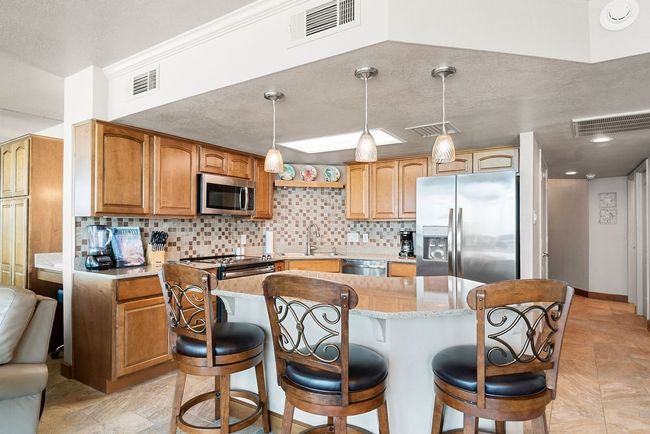 Kitchen has large island and additional seating. | Image 6