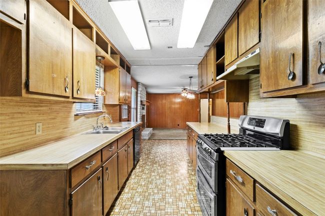 Kitchen featuring stainless steel range with gas stovetop, open shelves, ceiling fan, under cabinet range hood, and a textured ceiling | Image 8