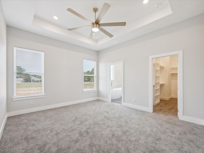 Unfurnished bedroom featuring a raised ceiling, carpet floors, a spacious closet, recessed lighting, and ensuite bath | Image 16