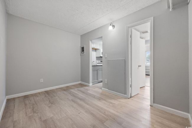 Empty room with a textured ceiling, light wood-style floors, and baseboards | Image 11