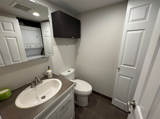 Bathroom featuring vanity, visible vents, tile patterned flooring, stacked washer / dryer, and toilet | Image 5