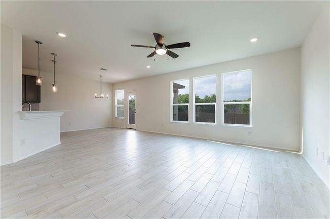 Unfurnished living room with a ceiling fan, a chandelier, light wood-style flooring, and recessed lighting | Image 15