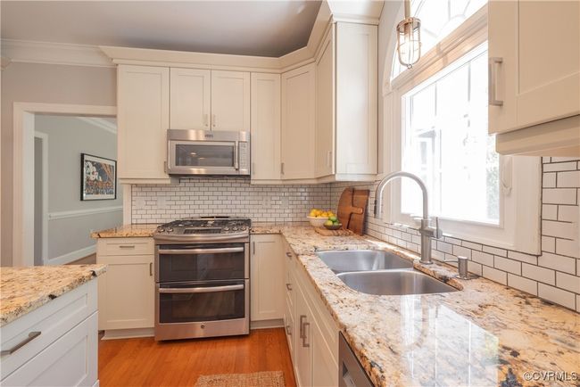Kitchen with tasteful backsplash, a sink, ornamental molding, appliances with stainless steel finishes, and light wood-style floors | Image 16