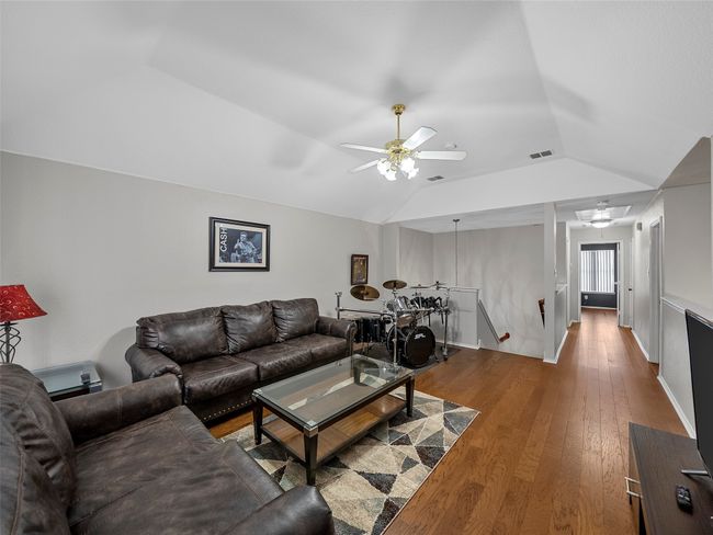 Living area featuring vaulted ceiling, a ceiling fan, wood finished floors, and visible vents | Image 32