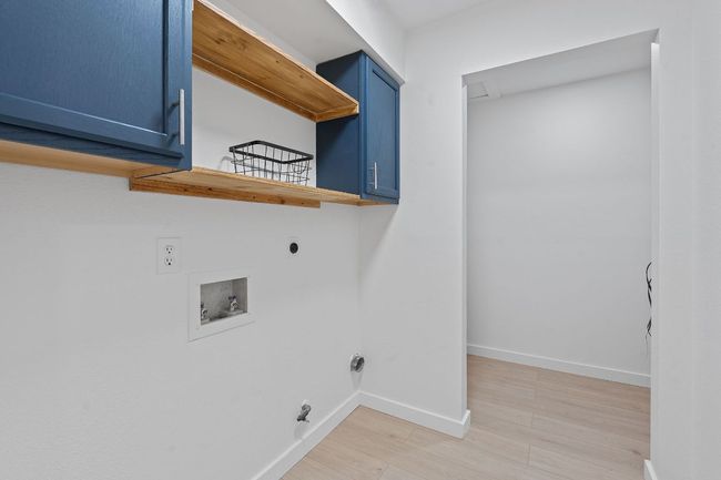 Laundry area featuring electric dryer hookup, cabinet space, washer hookup, and light wood-style floors | Image 30
