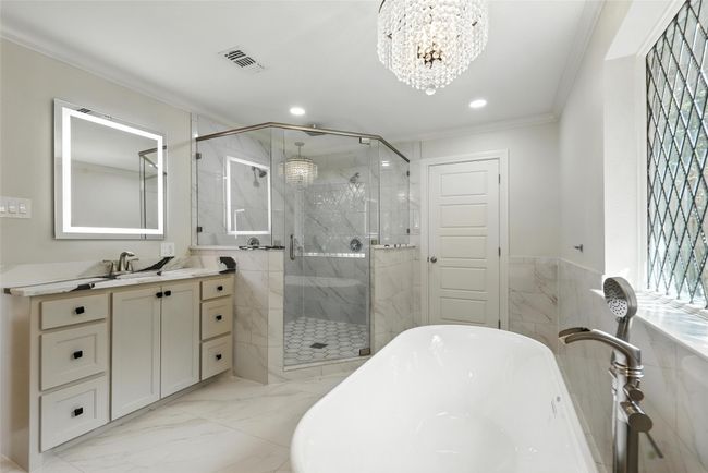 Full bathroom with ornamental molding, a marble finish shower, a freestanding tub, a chandelier, and marble finish flooring | Image 4