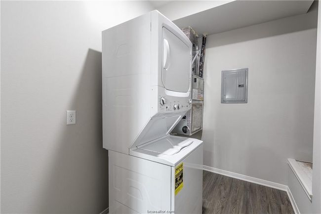 Washroom with stacked washer and dryer, dark hardwood / wood-style flooring, and electric panel | Image 21