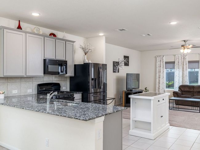 Kitchen with black appliances, open floor plan, open shelves, a ceiling fan, and light tile patterned floors | Image 9
