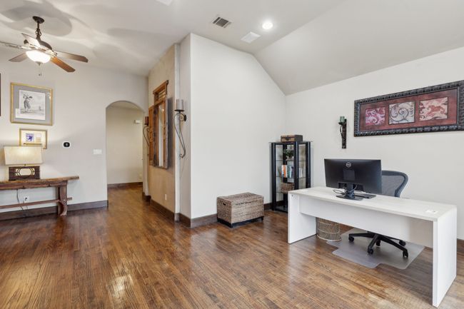 Home office featuring vaulted ceiling, wood finished floors, visible vents, arched walkways, and ceiling fan | Image 27