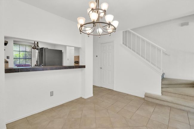 Kitchen with dark countertops, a chandelier, tile patterned flooring, and freestanding refrigerator | Image 10
