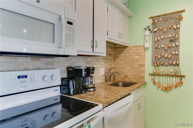 Kitchen with white appliances, light stone counters, a sink, decorative backsplash, and white cabinets | Image 6